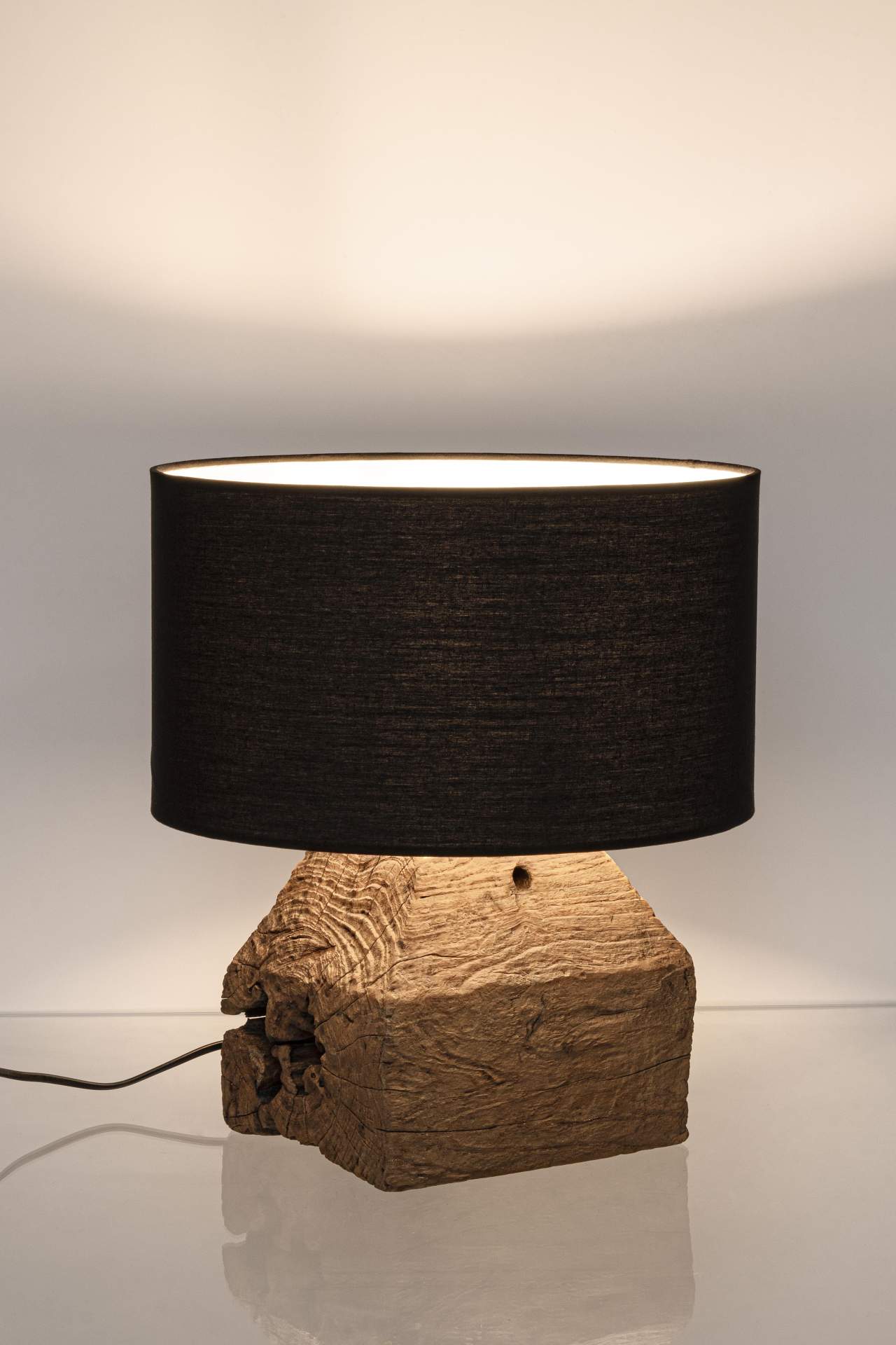 Die Tischleuchte Lumen überzeugt mit ihrem klassischen Design. Gefertigt wurde sie aus recyceltem Teakholz, welches einen natürlichen Farbton besitzt. Der Lampenschirm ist aus Baumwolle und hat eine schwarze Farbe. Die Lampe besitzt eine Höhe von 40 cm.