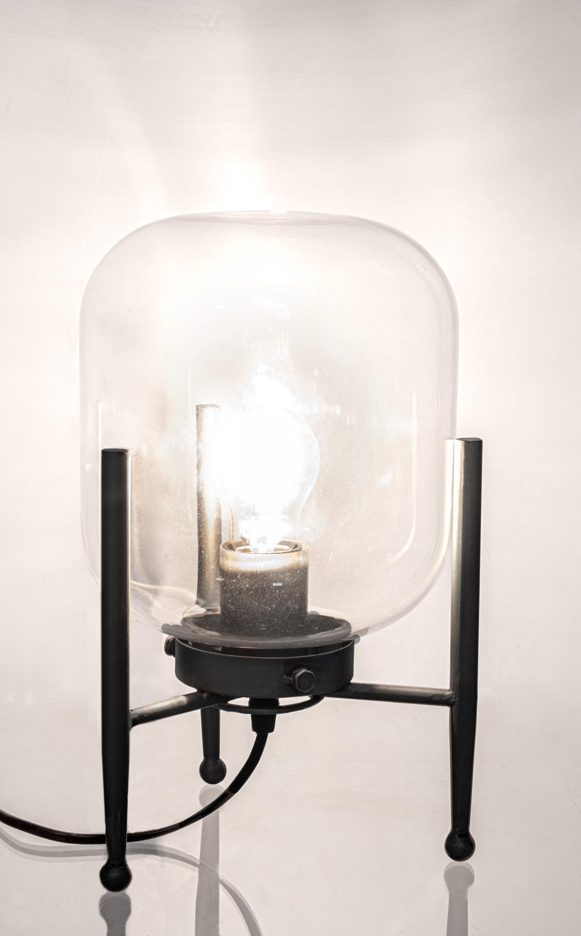 Die Tischleuchte Queer überzeugt mit ihrem klassischen Design. Gefertigt wurde sie aus Metall, welches einen schwarzen Farbton besitzt. Der Lampenschirm ist aus Glas.  Die Lampe besitzt eine Höhe von 38 cm.