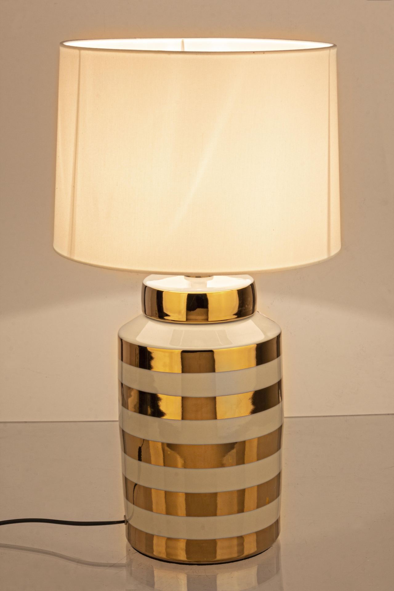 Die Tischleuchte Honey überzeugt mit ihrem klassischen Design. Gefertigt wurde sie aus Porzellan, welches einen goldenen Farbton besitzt. Die Lampenschirme ist aus Polyester und hat eine weiße Farbe. Die Lampe besitzt eine Höhe von 63 cm.