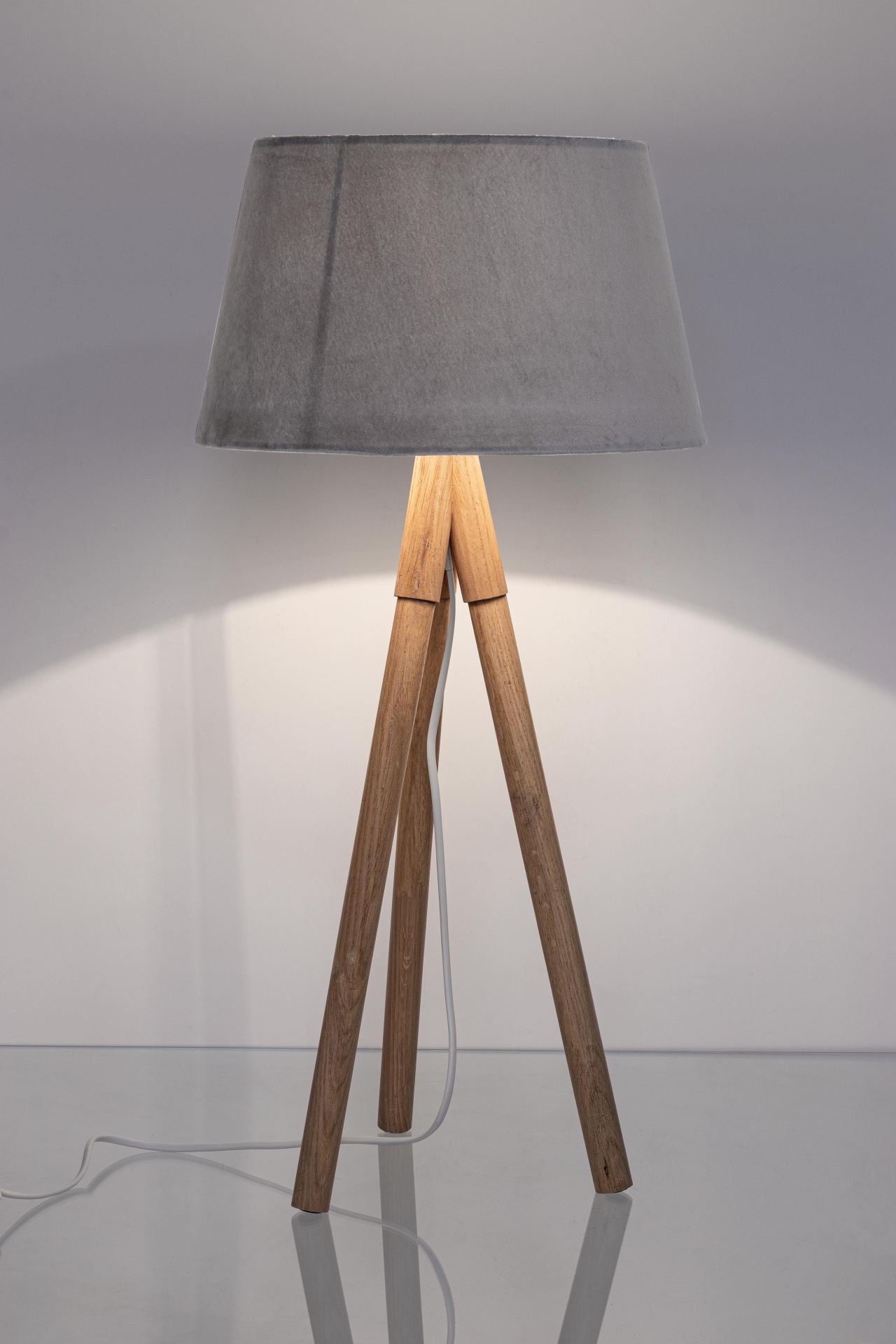 Die Tischleuchte Wallas überzeugt mit ihrem klassischen Design. Gefertigt wurde sie aus Tannenholz, welches einen natürlichen Farbton besitzt. Der Lampenschirm ist aus Samt und hat eine graue Farbe. Die Lampe besitzt eine Höhe von 69 cm.