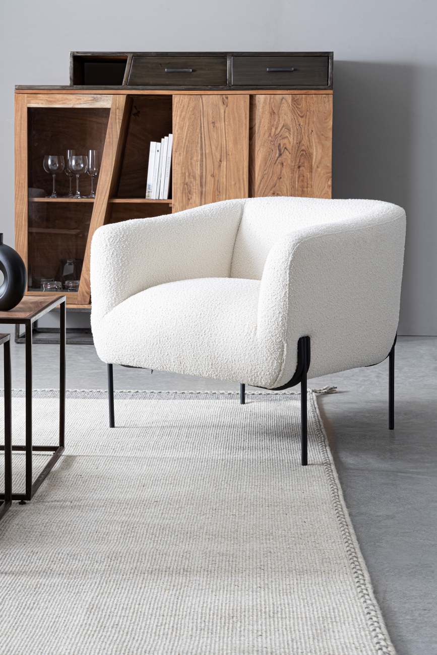 Der Sessel Claudine überzeugt mit seinem modernen Stil. Gefertigt wurde er aus Bouclè-Stoff, welcher einen weißen Farbton besitzt. Das Gestell ist aus Metall und hat eine schwarze Farbe. Der Sessel verfügt über eine Armlehne.