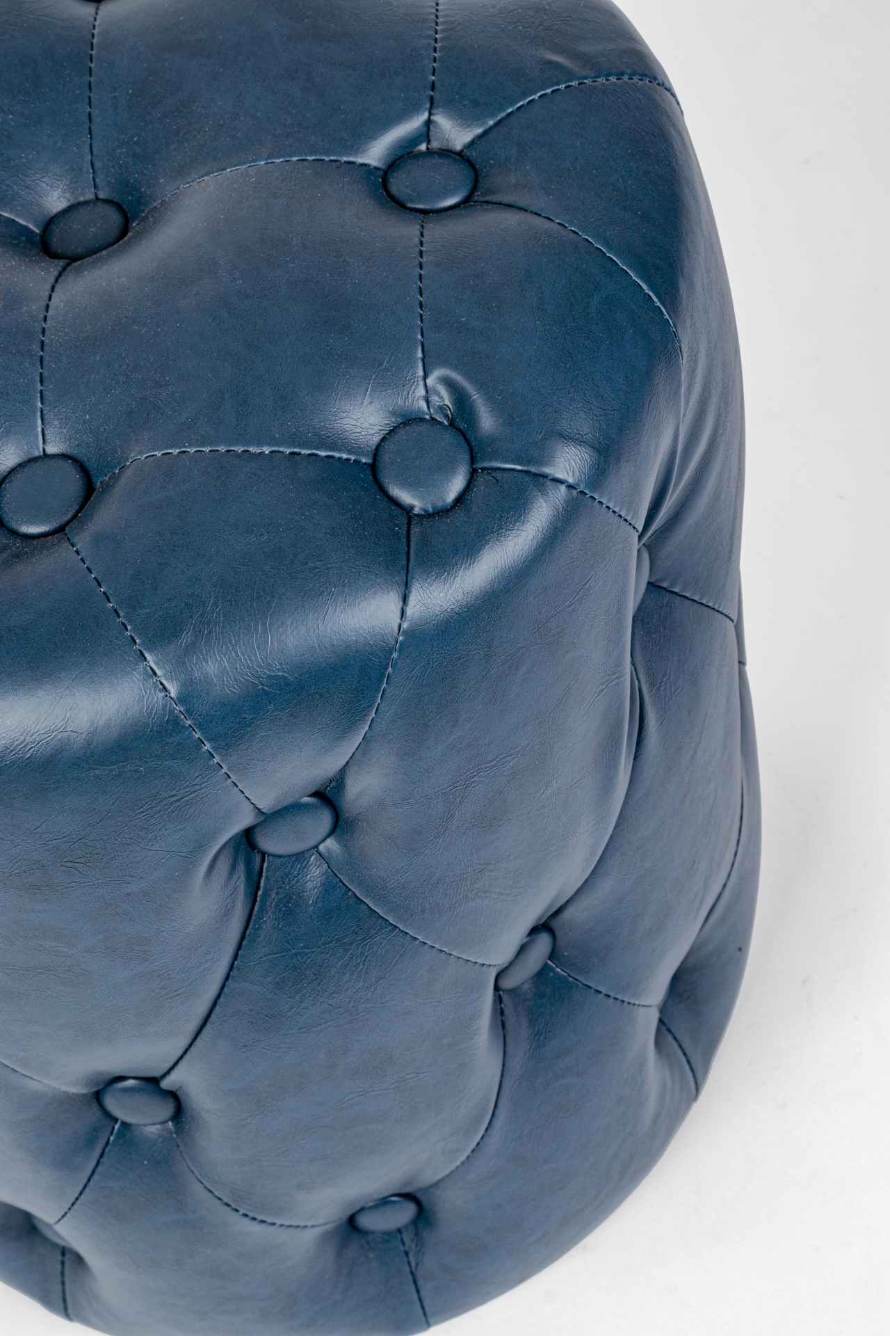 Der Pouf Batilda überzeugt mit seinem klassischen Design. Gefertigt wurde er aus Kunstleder in Chesterfiel-Optik, welches einen blauen Farbton besitzt. Das Gestell ist aus Kiefernholz. Der Durchmesser beträgt 34 cm.